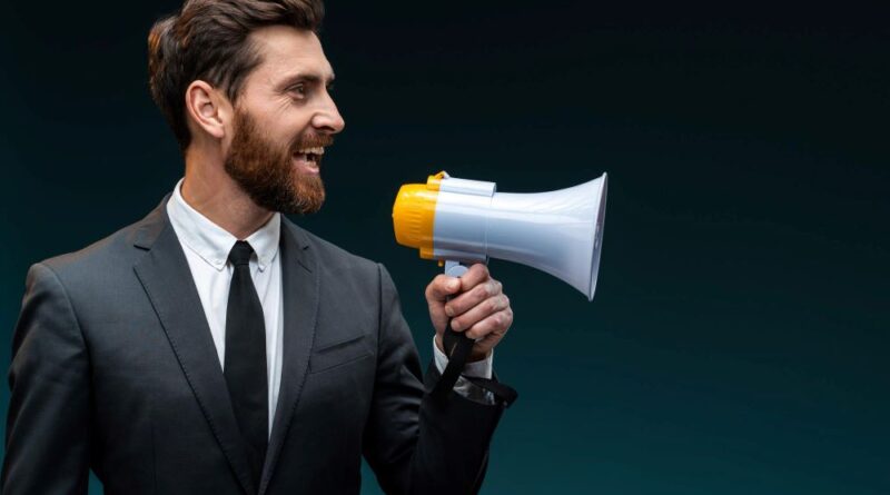 profile portrait of the friendly bearded businessman loudly speaking while holding megaphone